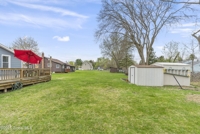 view of yard with a wooden deck, a storage unit, and an outbuilding