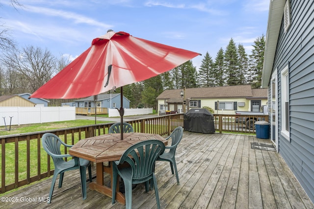 deck with fence, outdoor dining space, a yard, and a grill