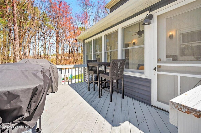 wooden deck with a sunroom and a grill
