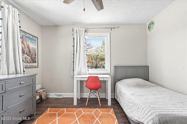 bedroom featuring a ceiling fan, a textured ceiling, visible vents, and dark wood-style floors