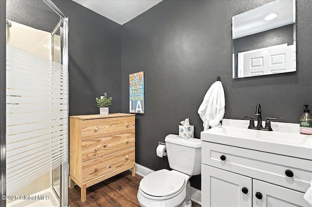 full bathroom with vanity, wood finished floors, toilet, baseboards, and a stall shower