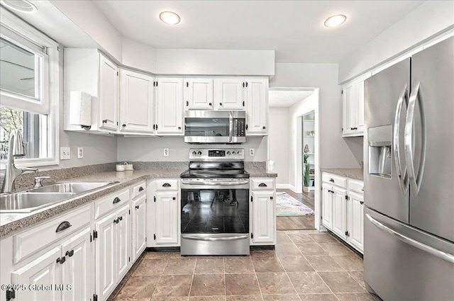 kitchen featuring a sink, appliances with stainless steel finishes, white cabinets, and light countertops
