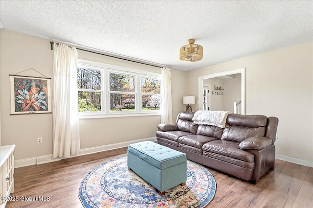 living room featuring a textured ceiling, baseboards, and wood finished floors