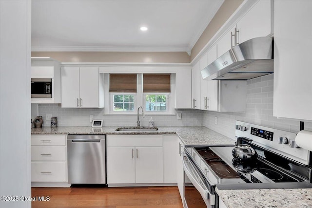 kitchen with appliances with stainless steel finishes, under cabinet range hood, a sink, crown molding, and white cabinetry