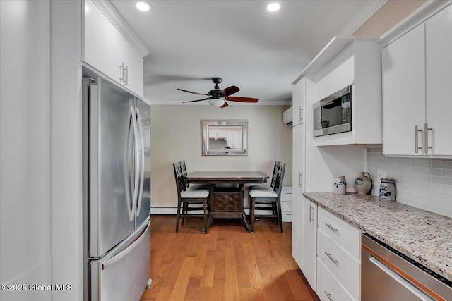 kitchen featuring appliances with stainless steel finishes, decorative backsplash, ornamental molding, a ceiling fan, and white cabinetry