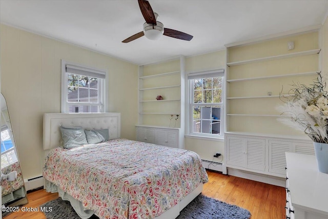 bedroom with a baseboard heating unit, multiple windows, and light wood-style flooring
