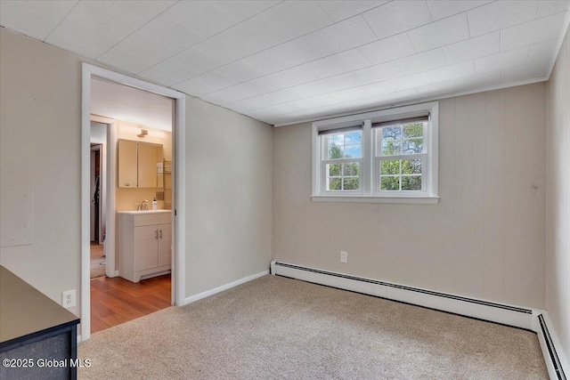 unfurnished bedroom with a baseboard heating unit, carpet, a sink, and connected bathroom