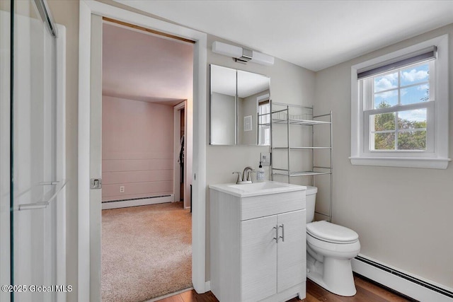 bathroom featuring a baseboard radiator, toilet, vanity, and wood finished floors