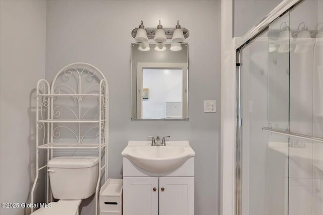 bathroom with toilet, a shower stall, and vanity