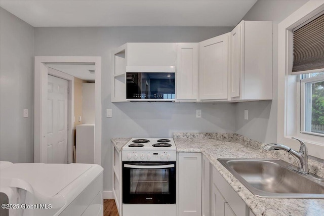 kitchen with white electric range oven, a sink, white cabinetry, and light countertops