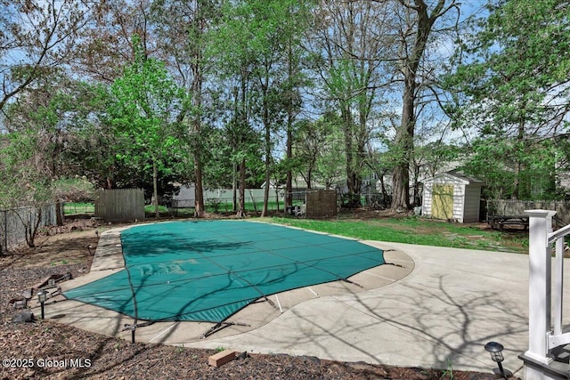 view of pool featuring a shed, a fenced backyard, a patio area, and an outbuilding