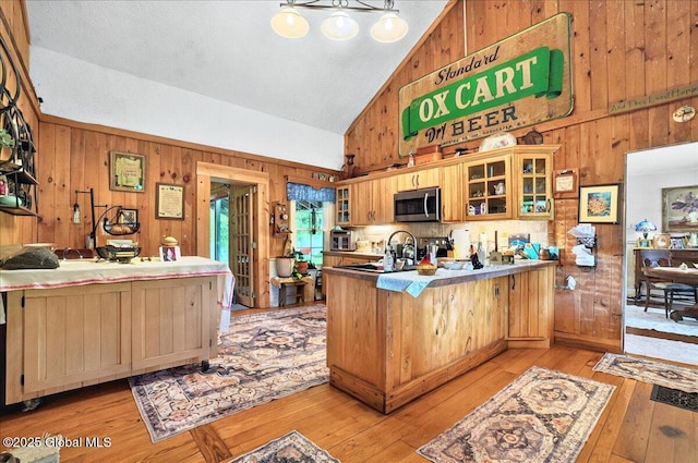 291-294 Gilchrist Hill Rd, Hartford, NY 12838 - kitchen featuring stainless steel microwave, wood walls, a peninsula, high vaulted ceiling, and light wood-style flooring