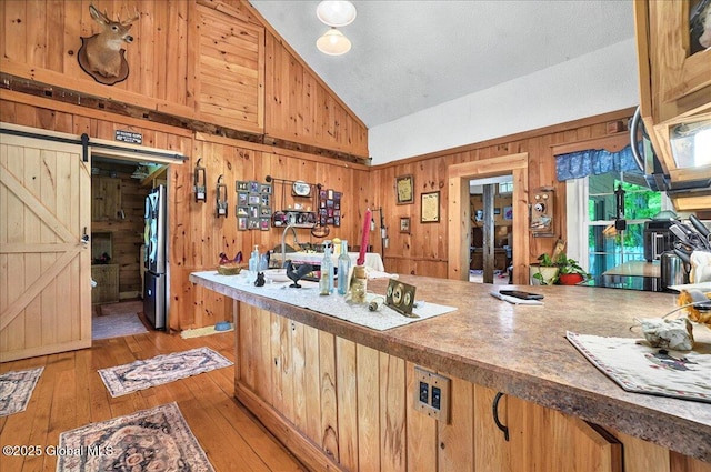 291-294 Gilchrist Hill Rd, Hartford, NY 12838 - kitchen with appliances with stainless steel finishes, a barn door, wood walls, light wood-type flooring, and high vaulted ceiling
