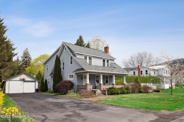 view of front facade featuring covered porch, a front yard, a chimney, an outbuilding, and a detached garage