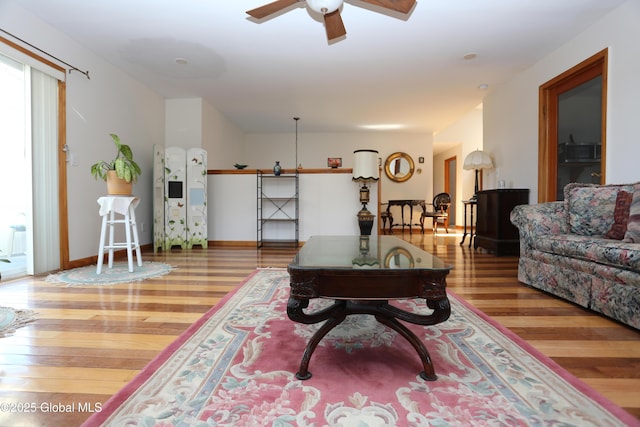 living room featuring baseboards, ceiling fan, and wood finished floors