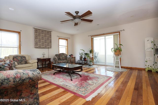 living room featuring baseboards, a baseboard radiator, wood-type flooring, and a ceiling fan