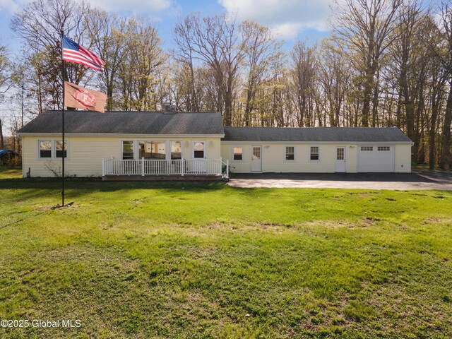rear view of house with a garage, a wooden deck, a chimney, and a yard