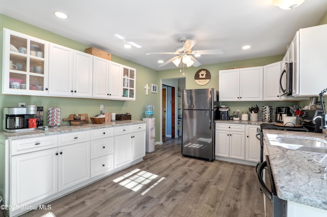 kitchen featuring ceiling fan, freestanding refrigerator, light wood-type flooring, and white cabinetry