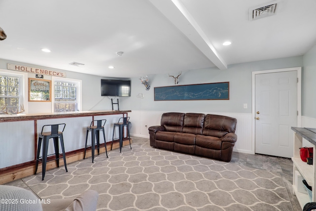 living area with a wainscoted wall, beamed ceiling, recessed lighting, and visible vents