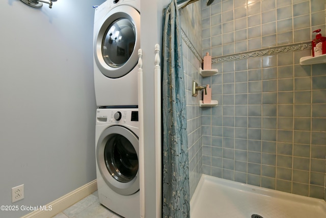 washroom featuring laundry area, stacked washing maching and dryer, baseboards, and tile patterned flooring