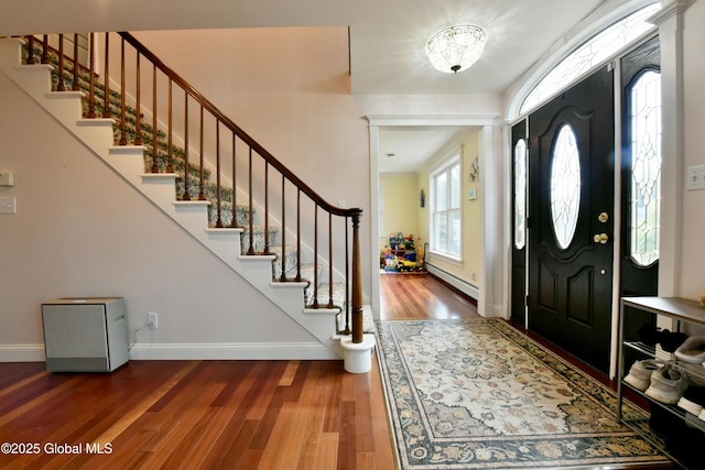 entryway with baseboards, a baseboard radiator, stairs, and wood finished floors