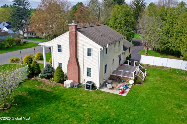 rear view of house featuring a deck, a fenced backyard, a chimney, a lawn, and a patio