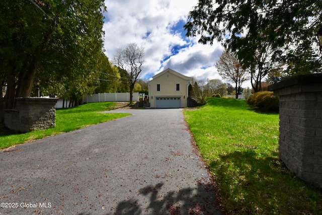 view of home's exterior featuring a lawn, a garage, aphalt driveway, and fence