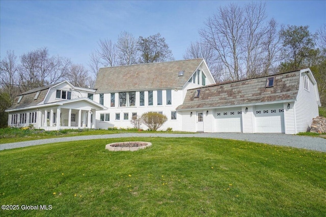 view of front facade featuring an outdoor fire pit, driveway, a front lawn, and a gambrel roof