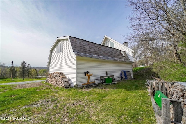 view of home's exterior featuring a gambrel roof, a yard, and a chimney