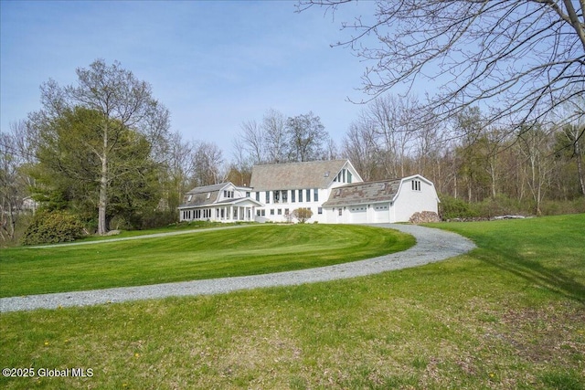 rear view of house with a garage, a yard, driveway, and a gambrel roof