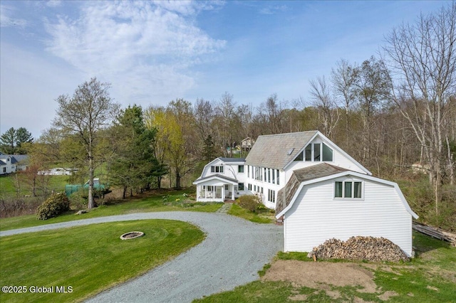 view of front of home featuring curved driveway, a gambrel roof, and a front lawn
