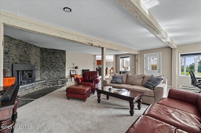 carpeted living area with a baseboard heating unit, beam ceiling, and a wood stove