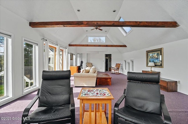 carpeted living area with a ceiling fan, beamed ceiling, a skylight, and high vaulted ceiling