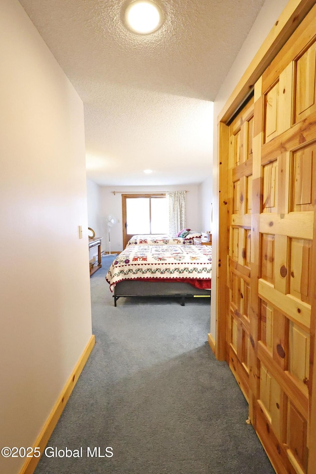 bedroom with a textured ceiling, carpet flooring, and baseboards