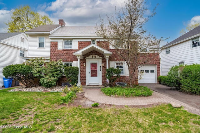 view of front of property featuring brick siding, a chimney, and aphalt driveway