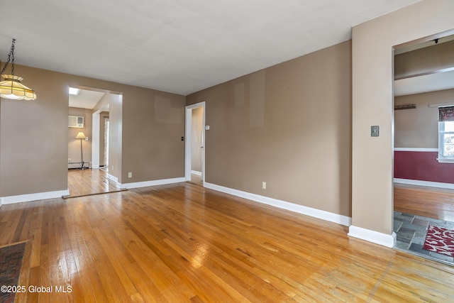 unfurnished living room with light wood-type flooring, baseboards, and an AC wall unit