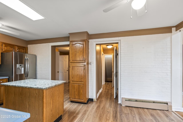 kitchen with brick wall, ceiling fan, light wood-type flooring, stainless steel fridge with ice dispenser, and a baseboard radiator