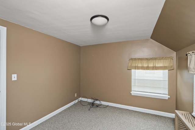 carpeted empty room with baseboards and vaulted ceiling