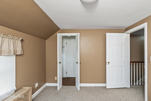 unfurnished bedroom featuring baseboards, vaulted ceiling, and carpet