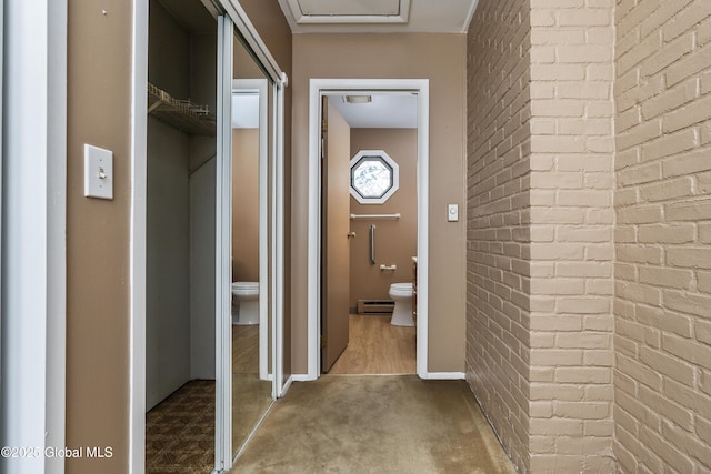 bathroom with baseboards, a baseboard radiator, brick wall, and toilet