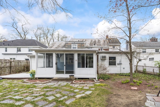 rear view of property with a sunroom, a fenced backyard, and a chimney