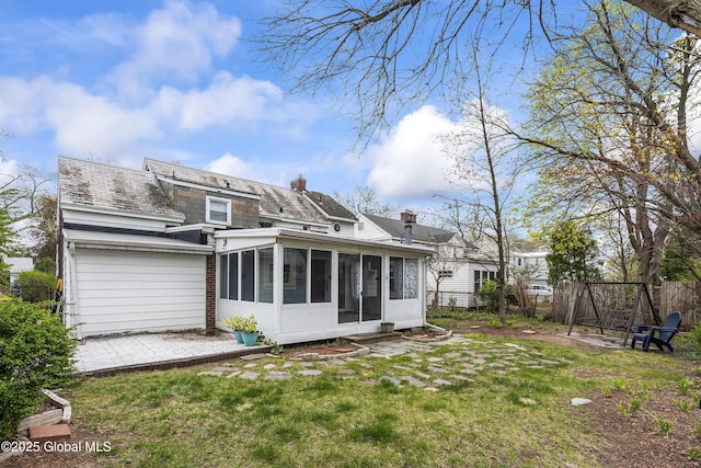 back of house with fence, a yard, a chimney, and a sunroom