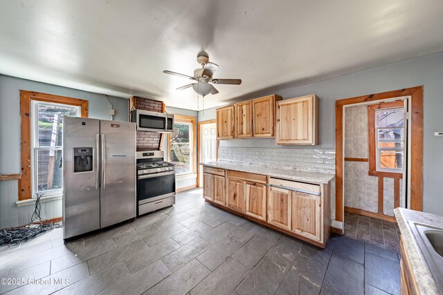kitchen featuring light brown cabinets, ceiling fan, light countertops, appliances with stainless steel finishes, and backsplash