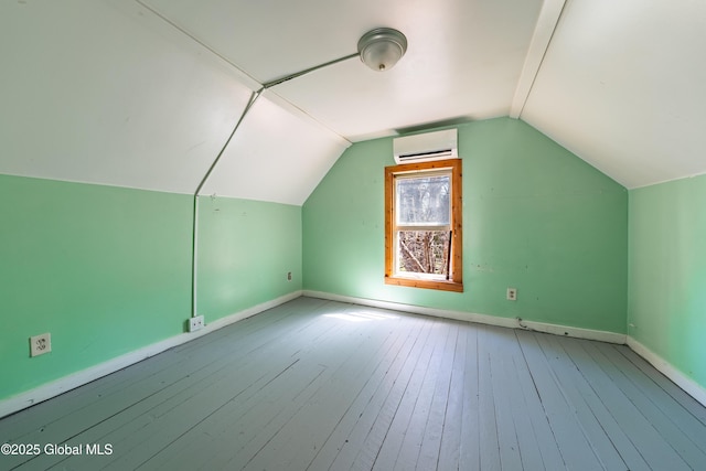 additional living space featuring wood-type flooring, baseboards, a wall mounted AC, and lofted ceiling