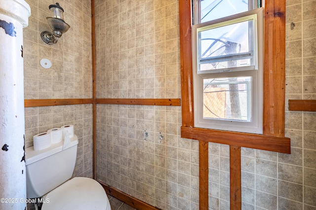 bathroom featuring tile walls and toilet