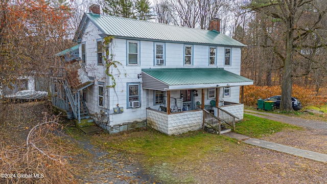 view of front of house featuring a chimney, a porch, and metal roof