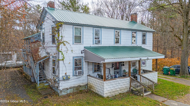 view of front of house featuring covered porch, a chimney, and metal roof