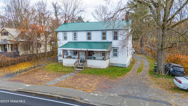 view of front of home with a porch, a chimney, and metal roof