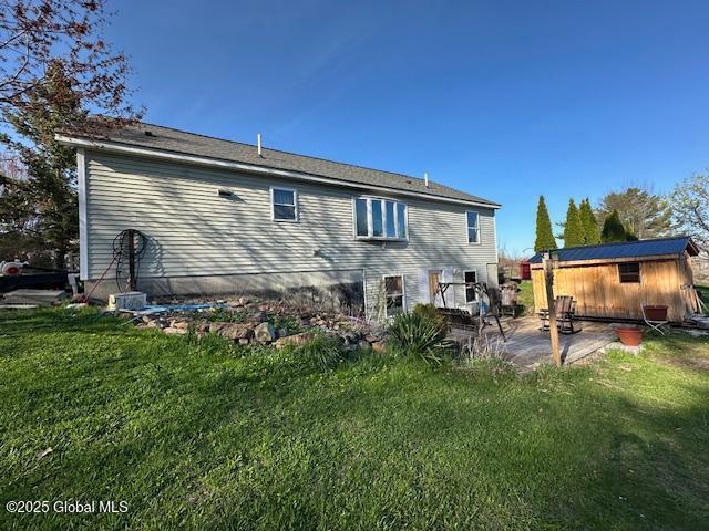 back of property featuring a yard, a patio, and an outbuilding