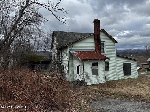 back of property with a chimney and metal roof